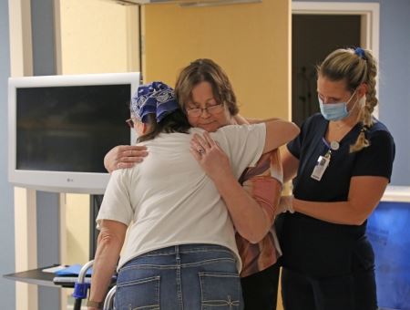 COVID Survivor Being Held By Nurse and Hugging Another Woman
